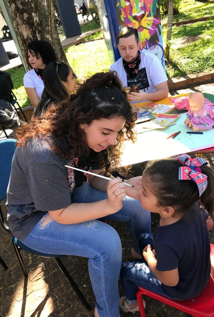 Aluna de Pedagogia pintando o rosto das crianças que estavam na praça